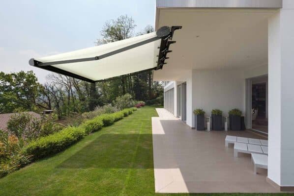 Klasična tenda ustvarja prijetno senco na terasi moderne hiše.